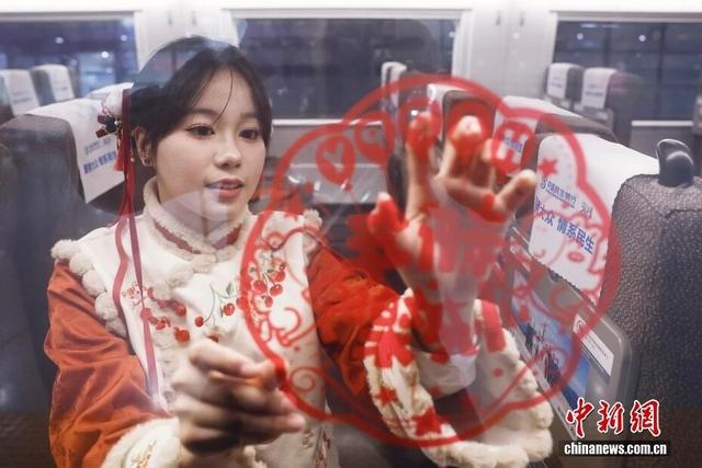 2月2日，列车员在高铁列车车厢内张贴新春主题窗花。中新社记者 殷立勤 摄