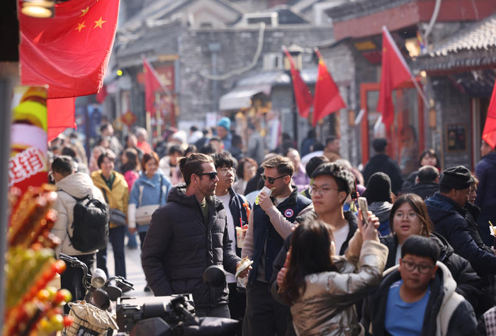 2月20日，烟袋斜街，外国游客品尝中国美食。新京报记者 李木易 摄