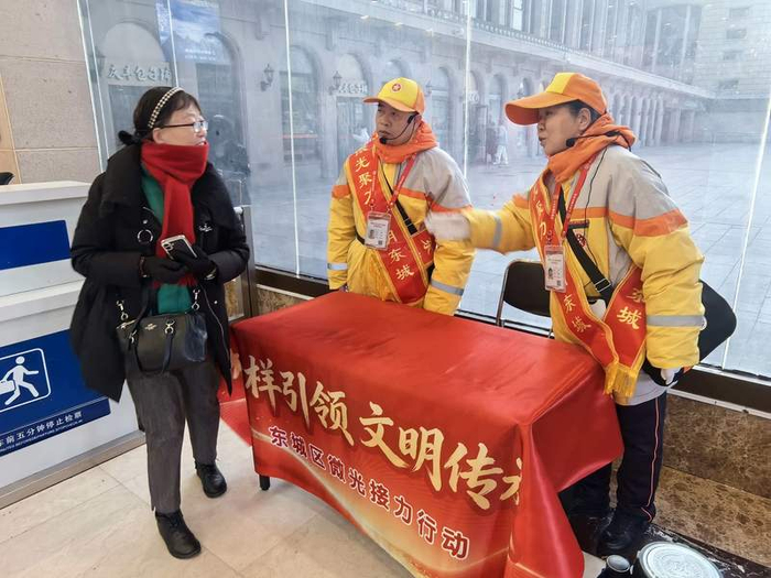 刘翚（右）做公共文明引导员已经17年，今年是她第一次走进北京站广场服务。