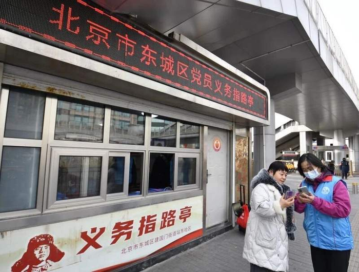 东城区建国门街道的站东义务指路队志愿者在北京站帮助旅客。