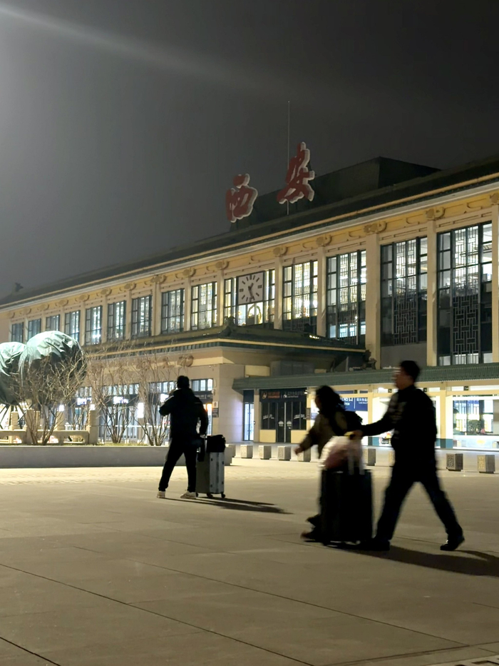 除夕夜，又一批乘客抵达西安，拖着行李箱走出火车站。新京报记者 丛之翔 摄