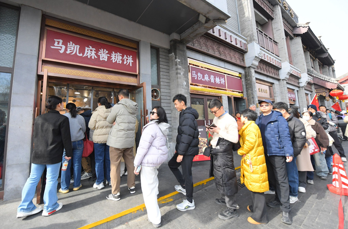糖饼、羊肉串……“逛吃”过年的消费者在特色老字号餐饮外卖窗口前排起长队。受访者供图