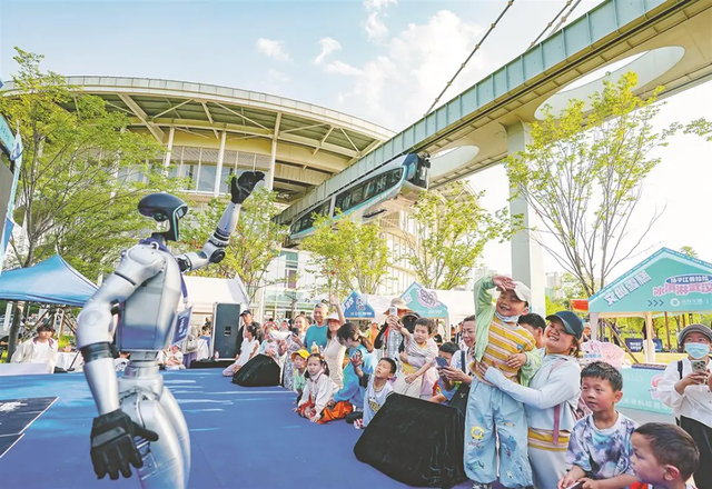 2025年5月1日，在武汉光谷空轨高新大道站，人形机器人与游客互动。湖北日报全媒记者 魏铼 摄