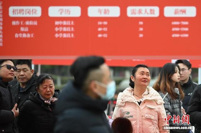 2月25日，江苏南京，应聘者在招聘摊位前查看招聘信息。中新社记者 泱波 摄