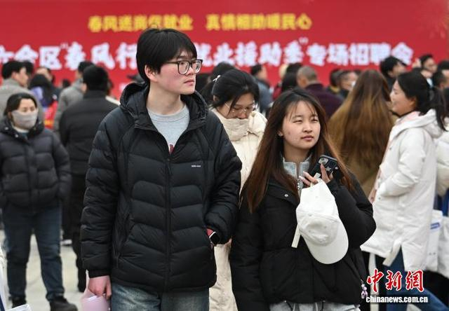 2月25日，江苏南京，应聘者在招聘摊位前查看招聘信息。中新社记者 泱波 摄