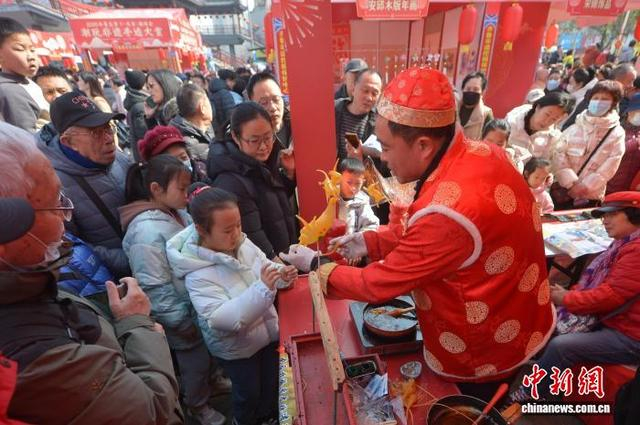 图为小朋友现场体验吹糖人。王海滨 摄