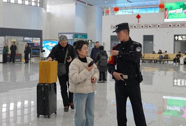 春运期间，铁路公安民警韩知航在通化站候车室内解答旅客提问。新华社记者 司晓帅 摄