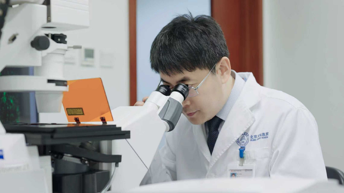 天坛医院常务副院长王伊龙通过共聚焦显微镜观察渐冻症样本免疫荧光染色。图源：天坛医院