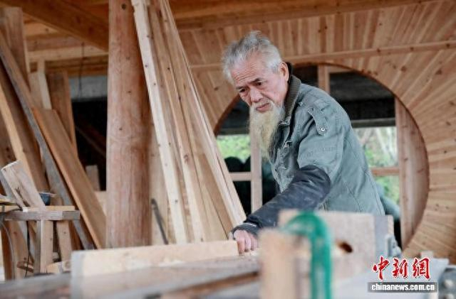 2月19日，在广西三江侗族自治县高培村，76岁侗族老人石善章在自家木楼工地里打磨木料。龚普康 摄