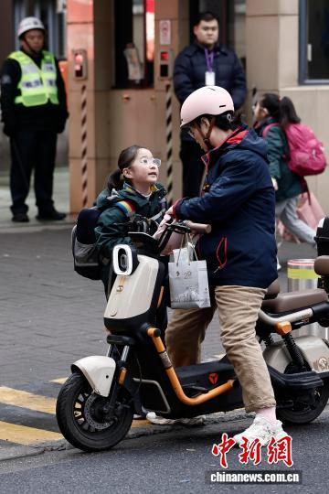 图为在上海市长宁区江苏路第五小学门口，家长送学生上学。中新社记者 殷立勤 摄