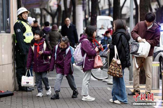图为在上海市长宁区江苏路第五小学门口，家长送学生上学。中新社记者 殷立勤 摄