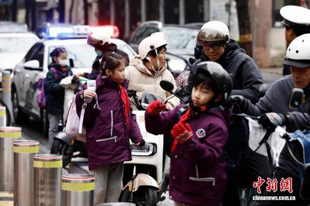 图为在上海市长宁区江苏路第五小学门口，家长送学生上学。中新社记者 殷立勤 摄
