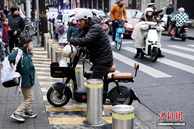图为在上海市长宁区江苏路第五小学门口，家长送学生上学。中新社记者 殷立勤 摄