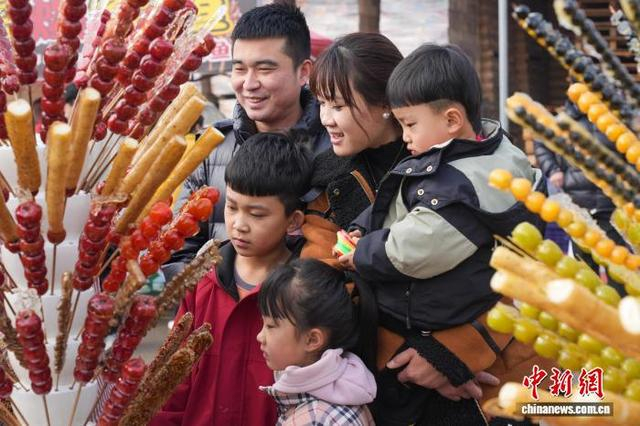 图为糖墩会上，游客为孩子挑选糖墩儿。 韩慧峰 摄