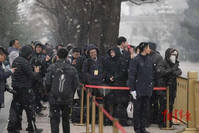 3月4日，北京，人民大会堂外，十四届全国人大四次会议发布会开始前，记者们在雪中等待入场。中青报·中青网记者 李隽辉/摄