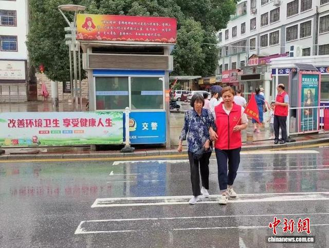 “学雷锋志愿服务”岗亭前，志愿者护送老人安全通过斑马线。受访者供图