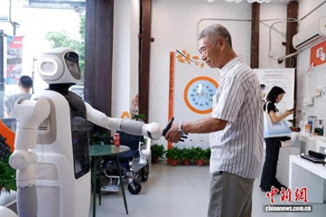 图为老人与智能康养机器人握手互动。 中新社记者 肖健 摄