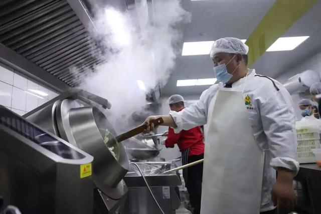 3月2日，鸦儿胡同小学微厨房里，厨师正在用智能炒菜机器人制作学生餐。新京报记者 李木易 摄