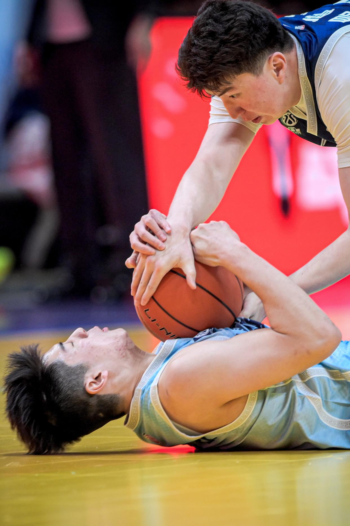 3月7日，大学生联队球员昂萨尔（上）与CBA星锐队球员陈家政在比赛中拼抢球权。新华社记者 江汉 摄