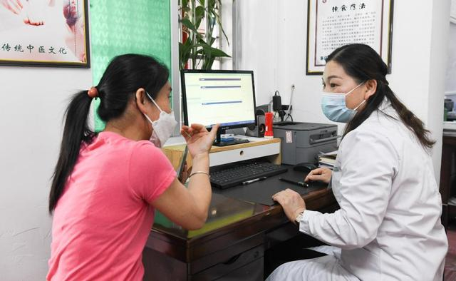 在海南省白沙黎族自治县七坊镇社区医院，韦小丽（右）在为病人看诊（图片摄于2023年2月13日）。新华社记者 杨冠宇 摄