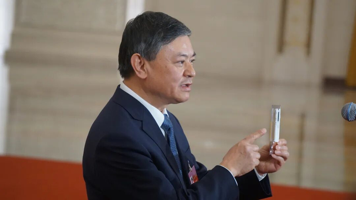 ▲生态环境部部长黄润秋现场展示芯片（何强 摄）