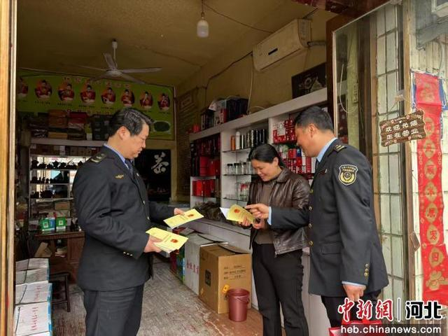 图为该县市场监督管理局工作人员向商户普及法律知识并发放宣传手册。 王佳琪 摄