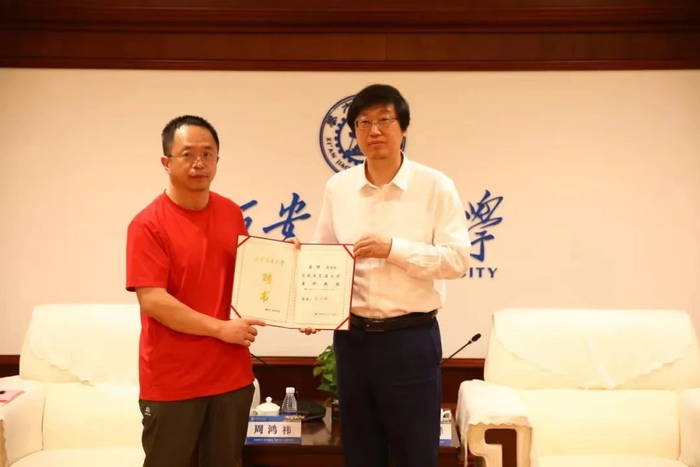 在周鸿祎校友兼职教授授聘仪式上，西安交通大学校长张立群为周鸿祎颁发了聘书，并为他佩戴校徽。（图源：西安交通大学校友会）