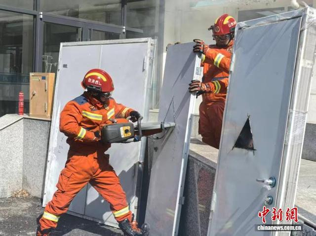 消防员现场切割防火门，对比展示优劣产品填充材料。 陆祁国 摄