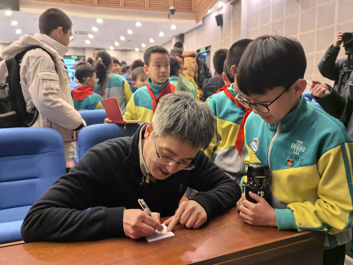 讲座结束后，刘若川被小学生围住，认真给孩子们签名。新京报记者 杨菲菲 摄