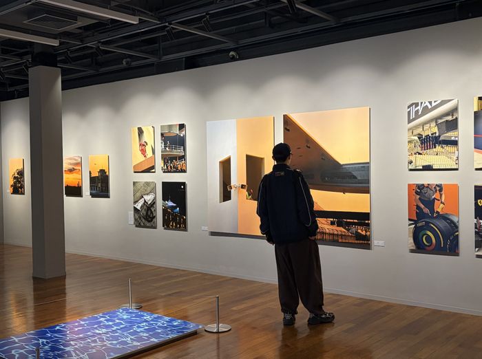 刘寒穿一身红牛车队标志性的“蓝”，在看周冠宇摄影展。（图/作者 摄）