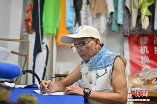 图为扬江诚为新款壮锦服饰绘制设计稿。俞靖 摄