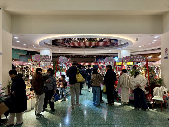 群众影剧院一楼设置了众多摊位，客流熙攘。