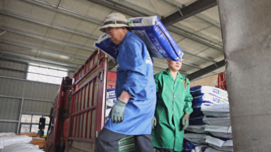 在益民农资有限公司内，工人们正在搬运肥料。都昌县融媒体中心供图