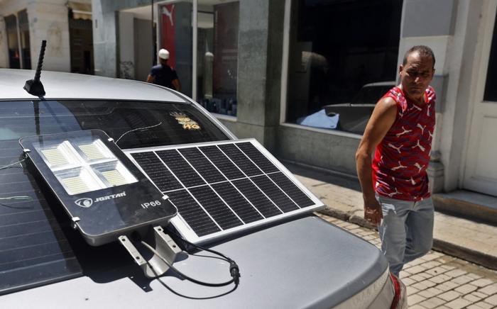 　2025年9月10日，古巴哈瓦那，一名男子看向为路灯供电的太阳能电池板。视觉中国 图