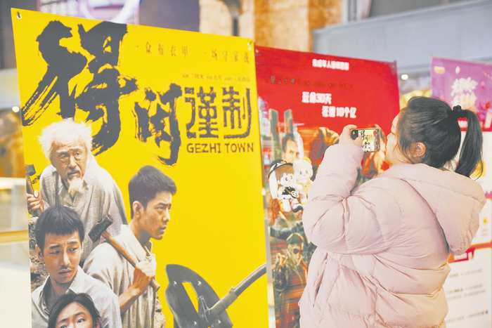 市民在北京一家影院的电影海报前打卡。 （视觉中国）