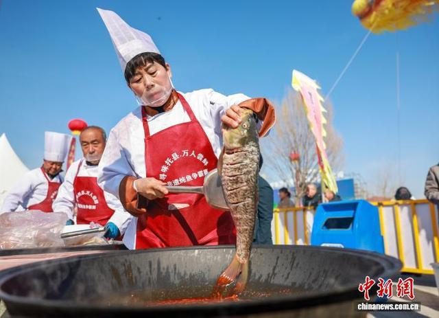 3月20日，内蒙古托克托县，炖鱼争霸赛中，参赛选手任秀清将一条黄河鲤放入锅中。 中新社记者 张玮 摄