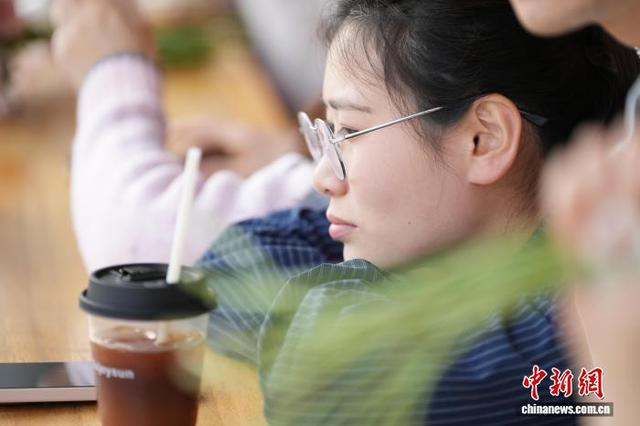 图为3月21日，游客一边品尝“瓜片美式”咖啡，一边观看窗外春景。刘鸿鹤 摄