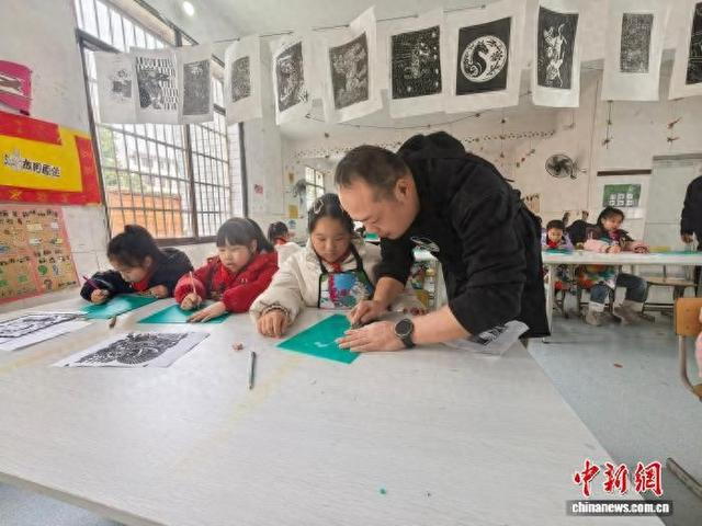 刘壮正在手把手教导孩子们画版画。 李胜财 摄