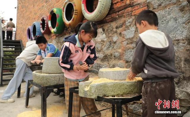 图为小朋友在体验磨米。陆荣斌 摄