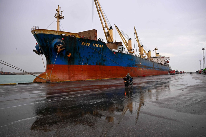 当地时间2026年3月12日，伊拉克巴士拉，一名码头工人骑摩托车经过在乌姆盖斯尔港停泊的货轮。视觉中国 图