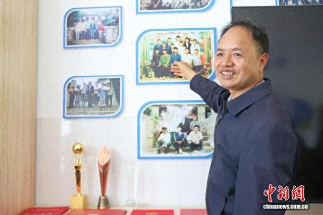 3月30日，农加贵指着墙上第一届毕业生的合影，逐一讲述学生们的去向与近况。王旭东 摄
