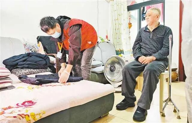 4月2日，璧山区璧泉街道太阳堡公租房，长护险护理员周伟（左）上门为失能老人服务。崔力摄/视觉重庆