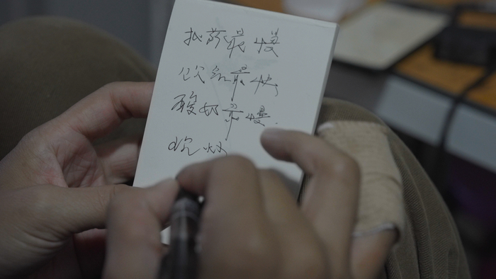 王晚做笔记，写字手的小拇指在骑行中受伤。新京报记者 吴瑜 摄 