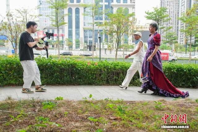 图为扬江诚与宋正开在南宁高楼间一处小花园拍摄走秀视频。中新社记者 陈冠言 摄 