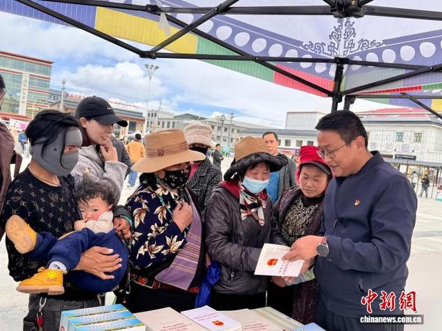 图为工作人员向驻足的各族青年和民众解读《中华人民共和国民族团结进步促进法》。祁绣娟 摄