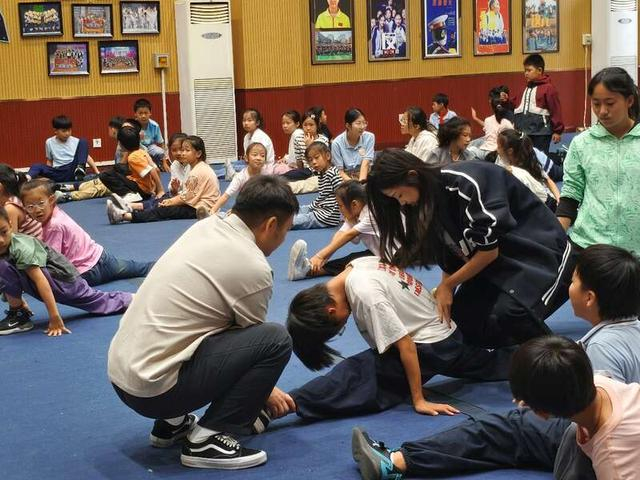 郑州市金水区金沙小学啦啦操社团教室里，马超群给孩子们压腿。实习生吴双双/摄