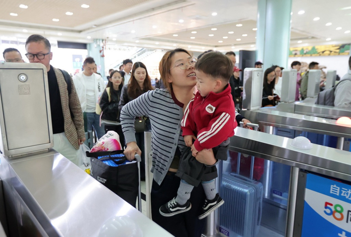 4月29日，江苏扬州，旅客抱着孩子在扬州火车站乘车出行。