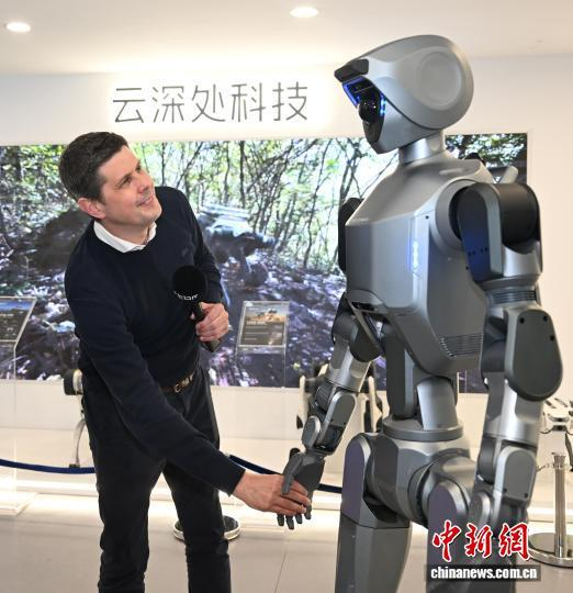 4月29日，同行的比利时记者和人形机器人握手。中新社记者 王刚 摄
