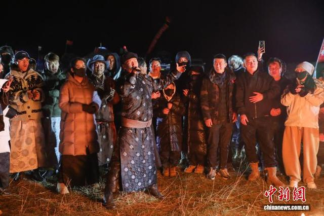图为当日晚间，游客与当地民众围着篝火载歌载舞。中新社记者 马铭言 摄 