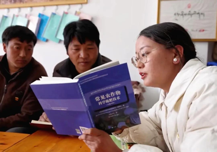 图为科技专干斯朗曲珍（右一）在与村民们一起讨论研究农作物种植技术。